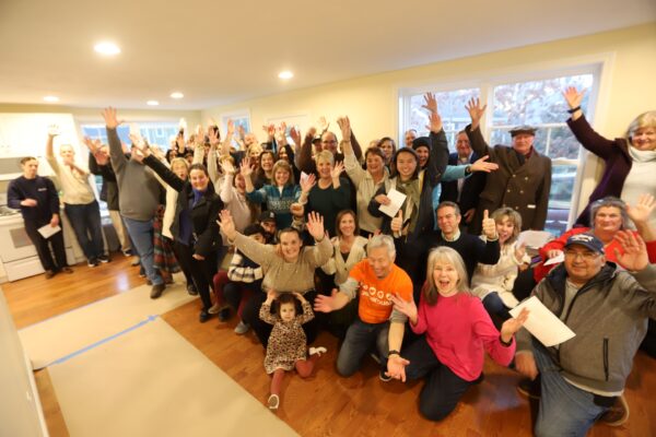 Members of the community gather together with Habitat for Humanity of Greater Plymouth volunteers, staff members, and the newest homeowner family in celebrating completion of the Strand Avenue home.